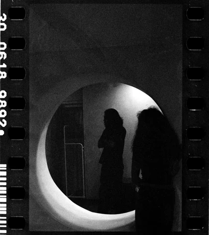 Two figures reflected in a circular mirror in a black-and-white session photograph